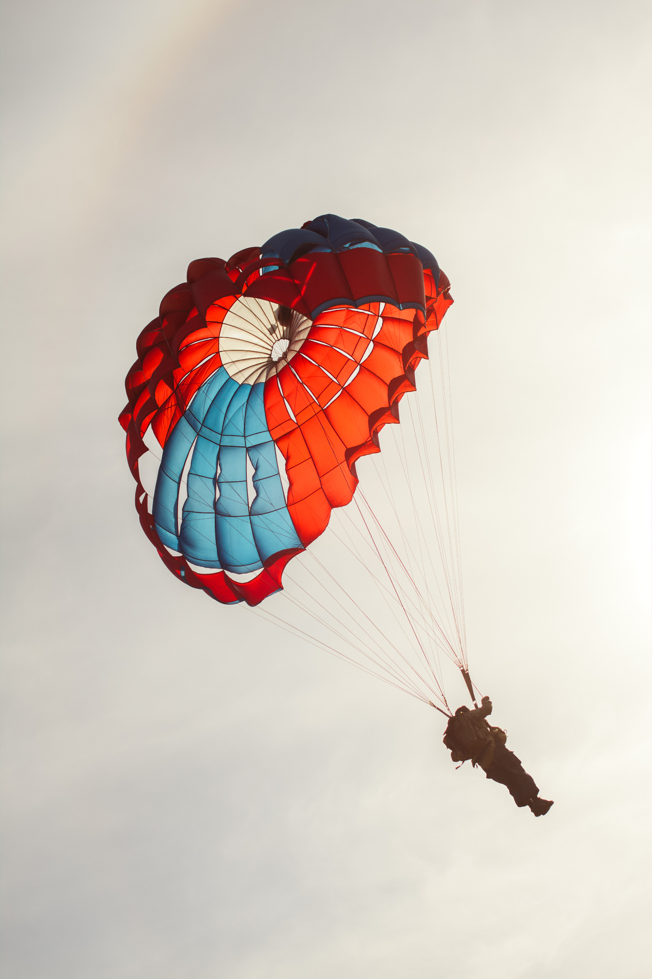A parasailer drifting under a red and blue canopy