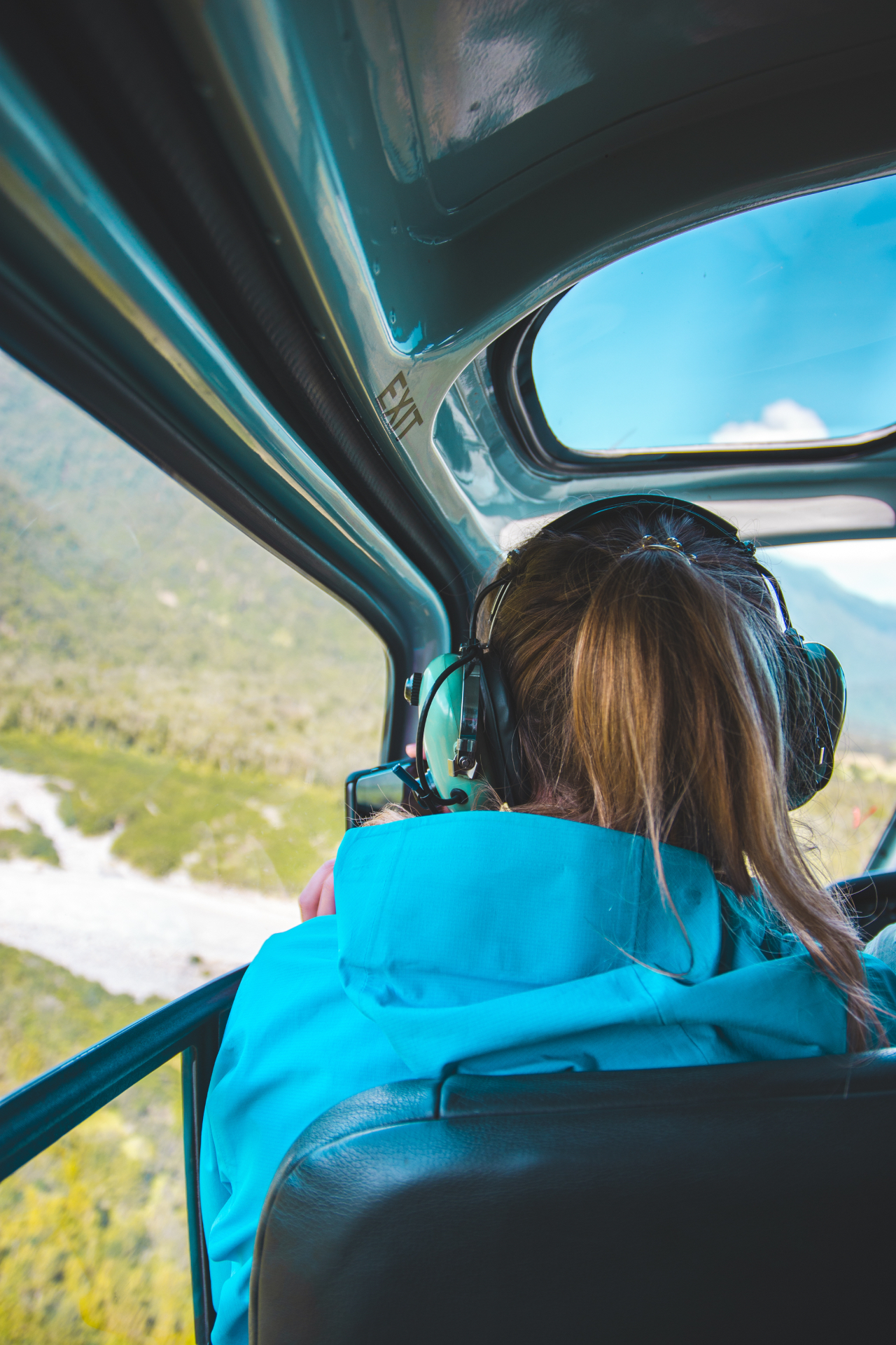 A passenger looking out over green valleys from a helicopter