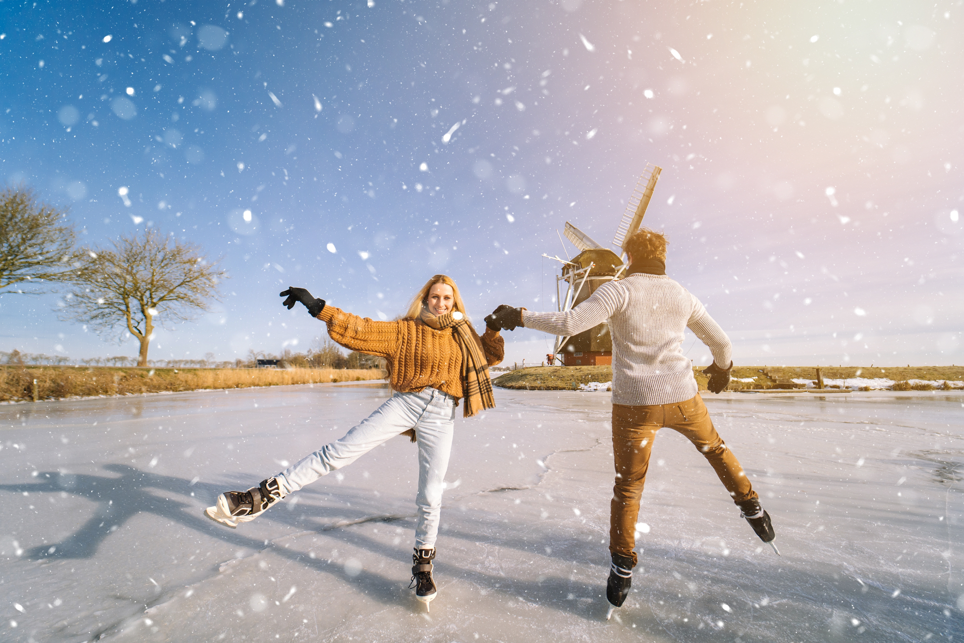 A couple ice skating on a frozen canal in the snow