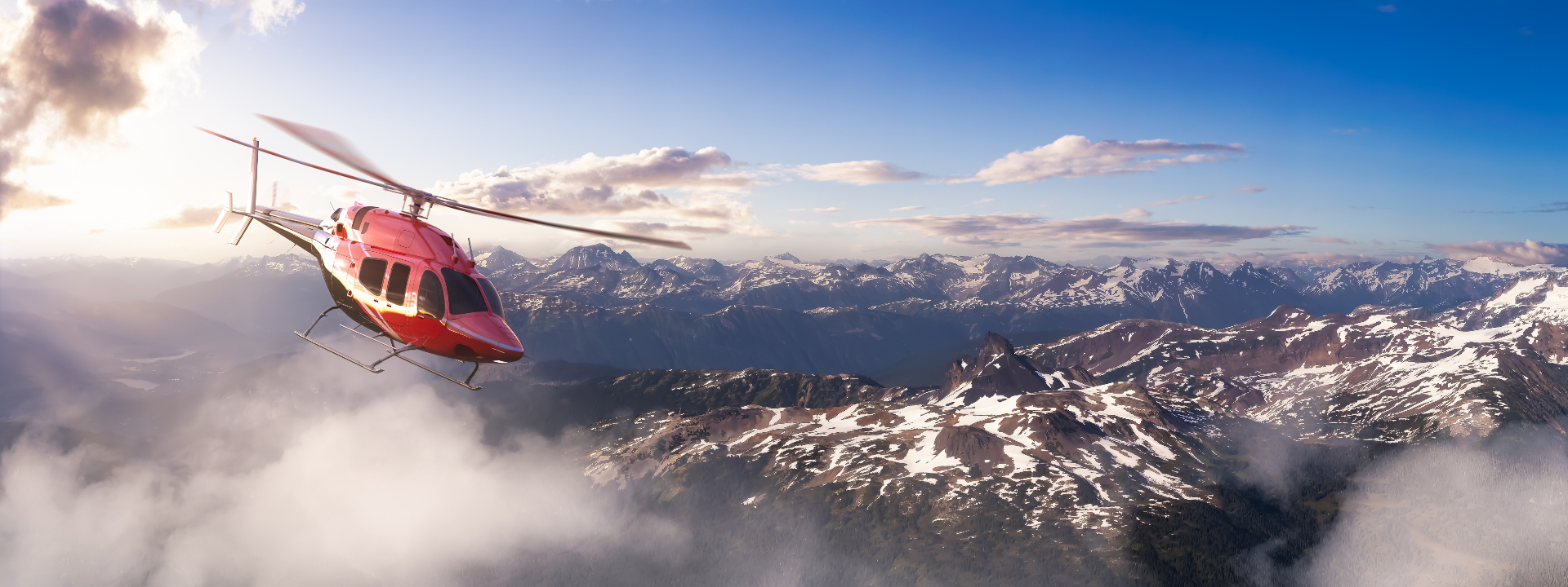 A helicopter flying above snow-capped mountains at sunrise