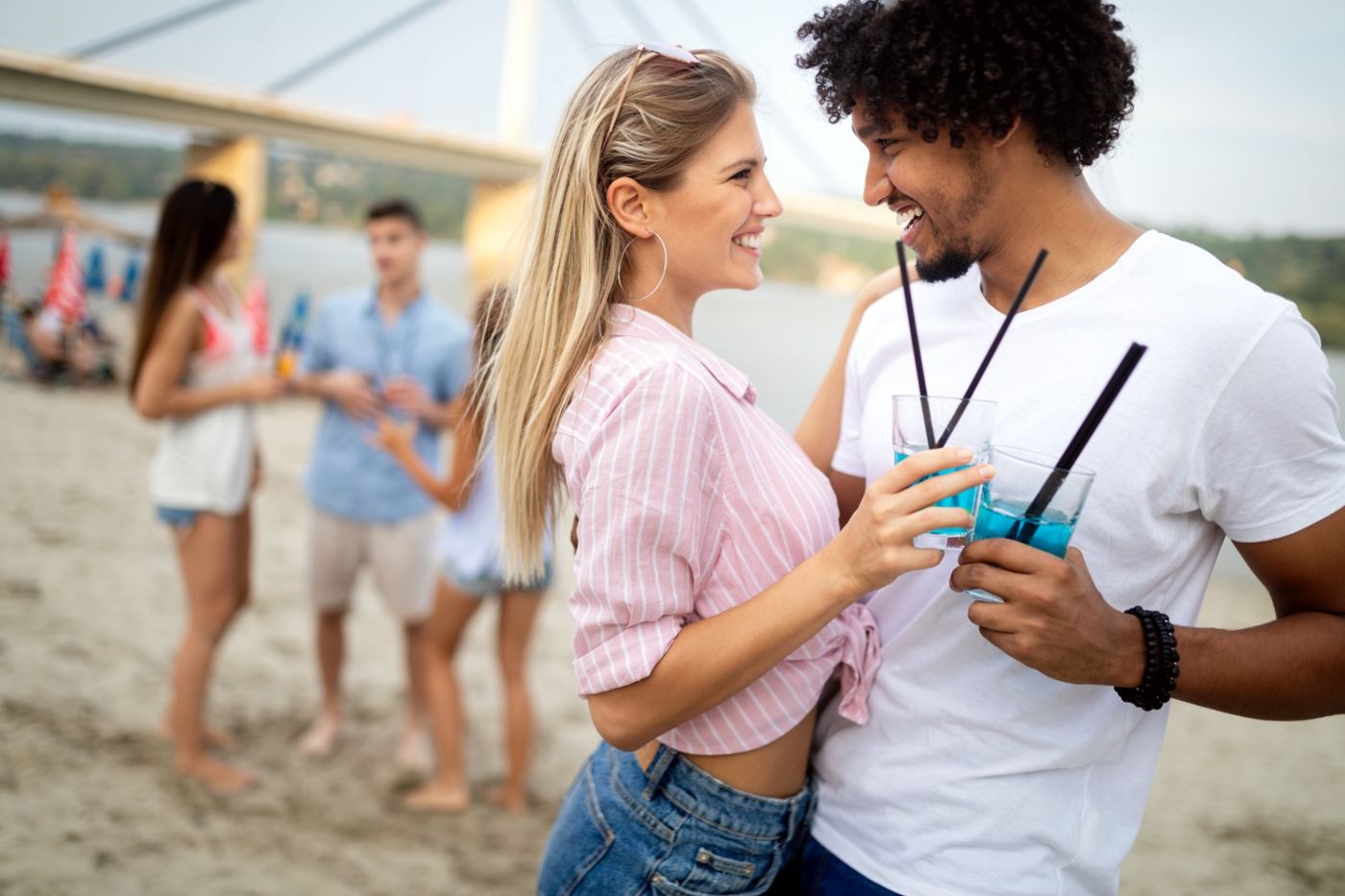 A couple sharing drinks together on a sunny beach